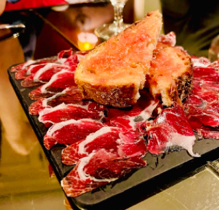 Platter of sliced jamón with pieces of bread topped with Spanish meat delicacy.